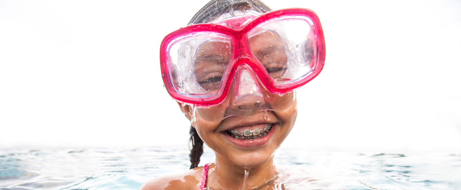 child with braces wearing goggles smiling for the camera